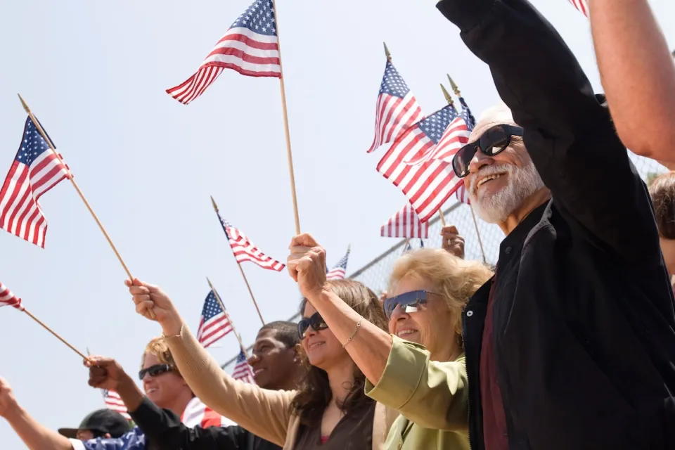 Group of senior citizens waving small American flags.